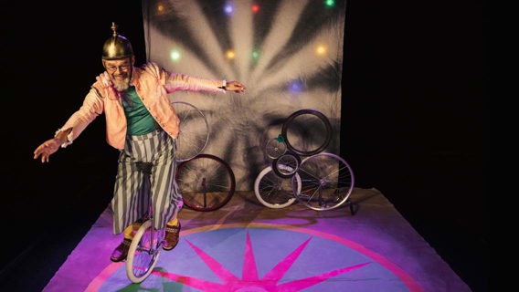 ett foto från en teater med en person som cyklar på en enhjuling