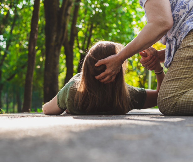 Kvinna knäböjer och hjälper annan kvinna upp som ligger på golvet