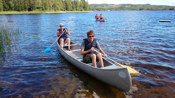 Två glada lägerdeltagare paddlar kanot