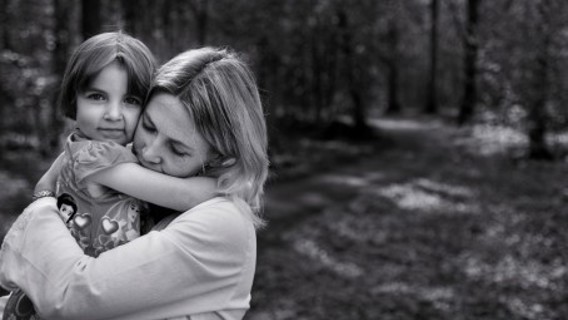 en mamma som kramar om sin dotter