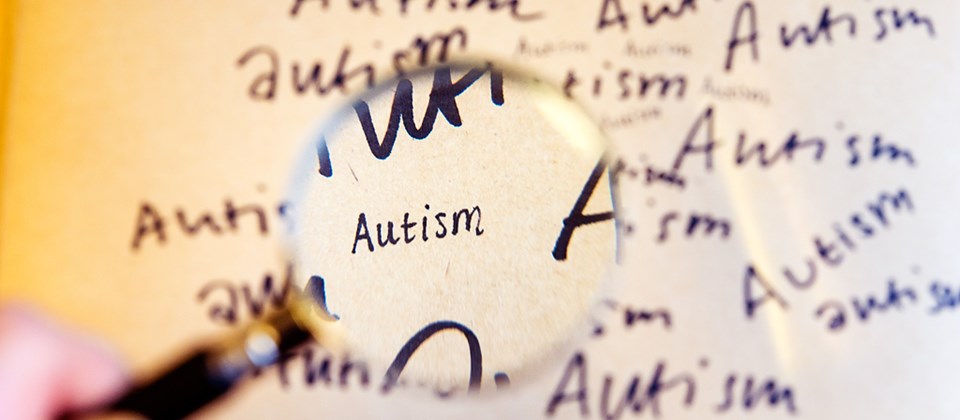 Ett förstoringsglas hålls över ordet autism.