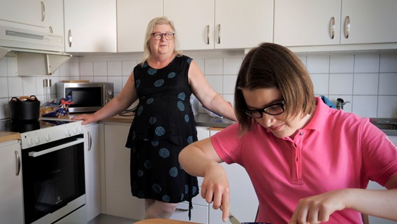 Jenny äter vid köksbordet och mamma Birgitta står bakom vid köksbänken
