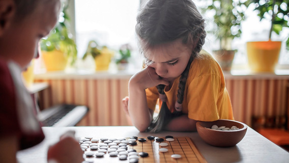 En flicka sitter vid ett bord och spelar spel