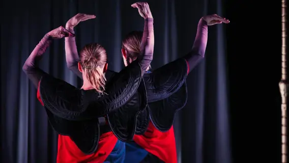 ett foto från en teater med två personer som håller upp armarna som fåglar