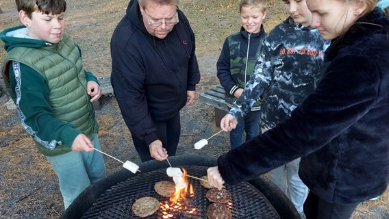 Barn och vuxna grillar marshmallows